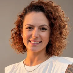 Retrato de Marjorie Pires sorrindo, de cabelo cacheado.